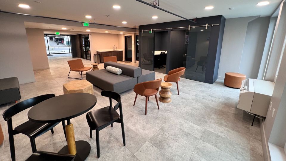 Large lounge with modern sectional couches, study rooms, and long laptop bar.