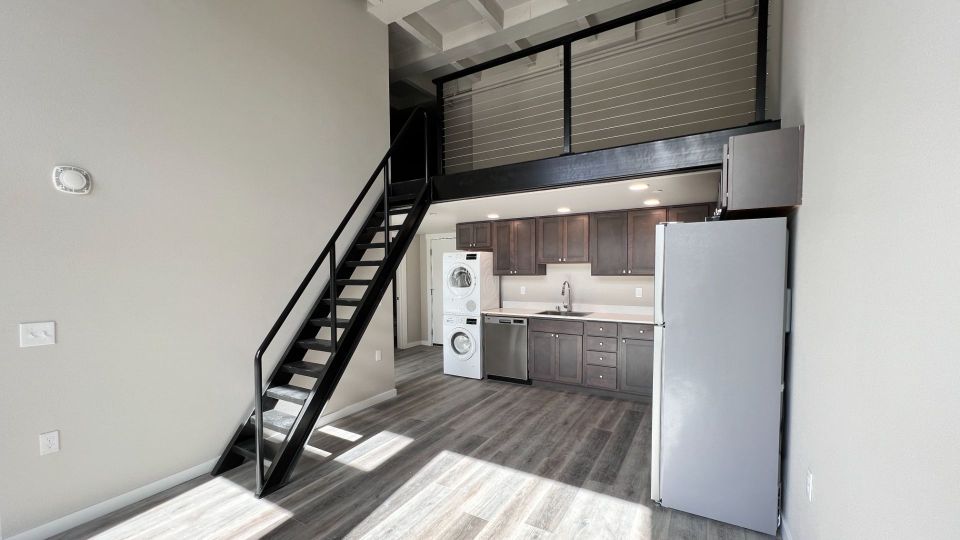 Loft Floor plan with bright kitchen with white countertops, stainless steel appliances, and walnut-colored cabinets.