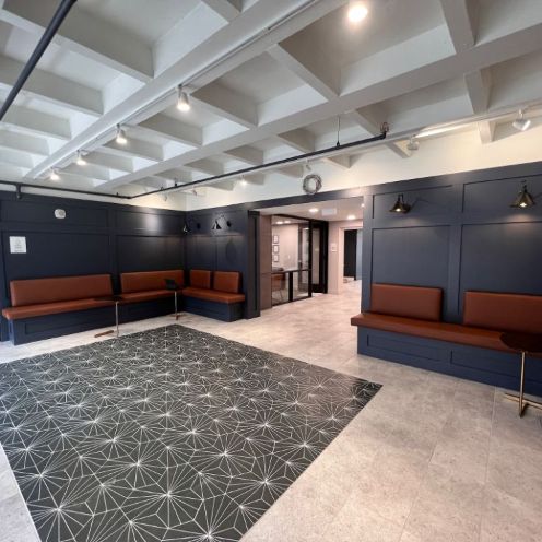 View of 508 West's modern lobby with black and white art deco accents, dark blue framed walls, and wrap around bench seating.