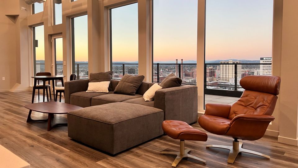 Large lounge with tall ceilings and rooftop views. Outdoor patio with firepit, table umbrellas, and lounge chairs.