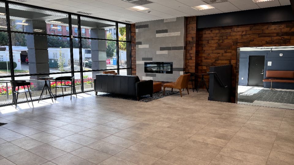 Large lobby area with wood paneling, dark blue walls, midcentury modern cafe tables and chairs.