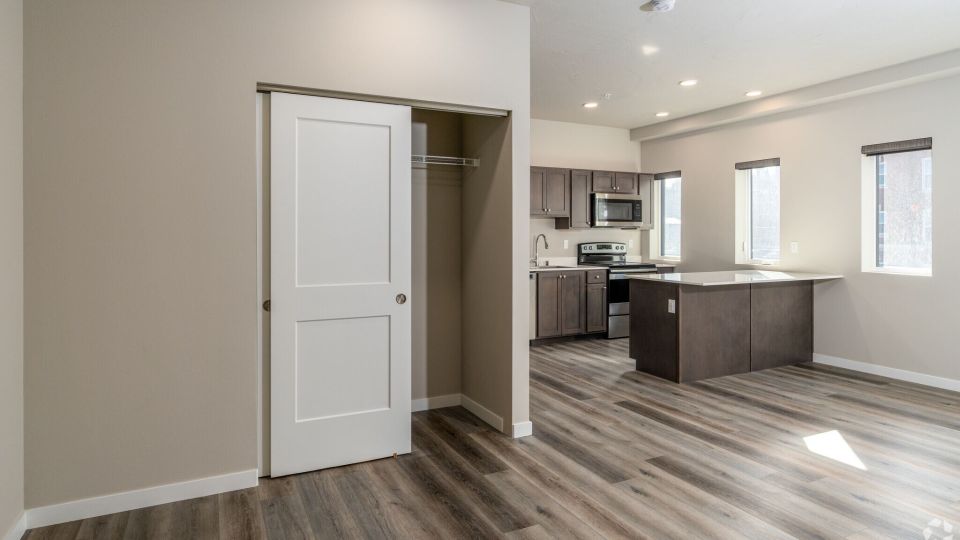 View of large studio layout with open concept kitchen with large island and bright windows.