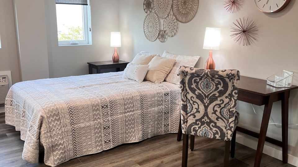 Livingroom bedroom studio area with L shaped kitchen floorplan, tall ceiling and recessed lighting.