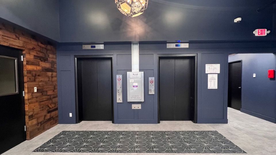 Midcentury modern and art deco style waiting area outside two elevators with crystal chandelier.