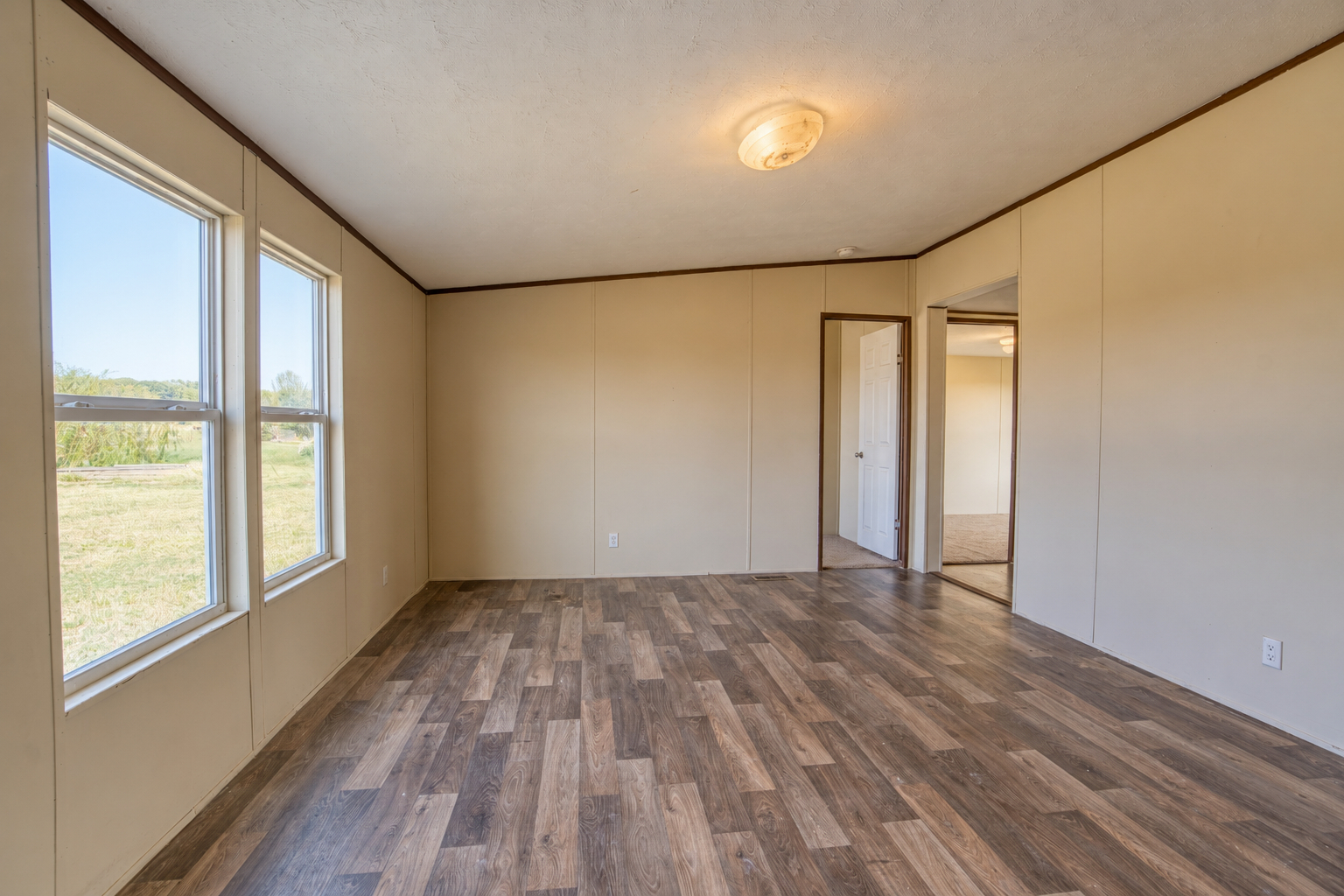 Living room with large windows and wood-look flooring - 215 Cale Lane, Calera OK
