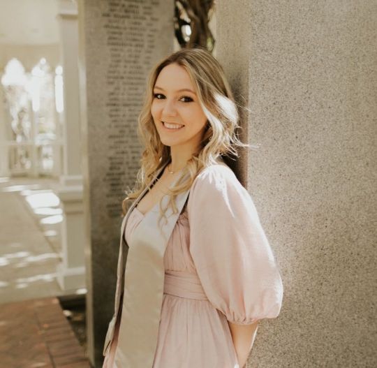 Portrait of Kenzie G, smiling and friendly standing outside