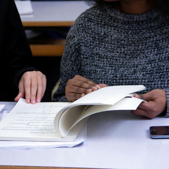 Student sitting on the bed working on school work on a laptop.