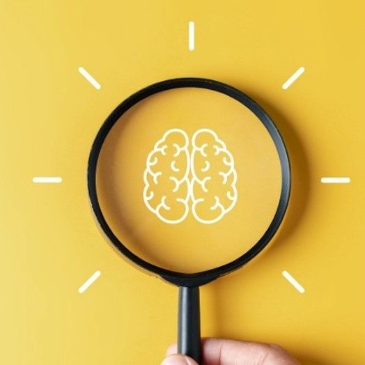 Cartoon drawing of a brain being inspected with a magnifying glass. 