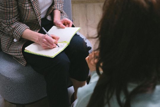 Therapist sitting close to someone taking notes on a notebook