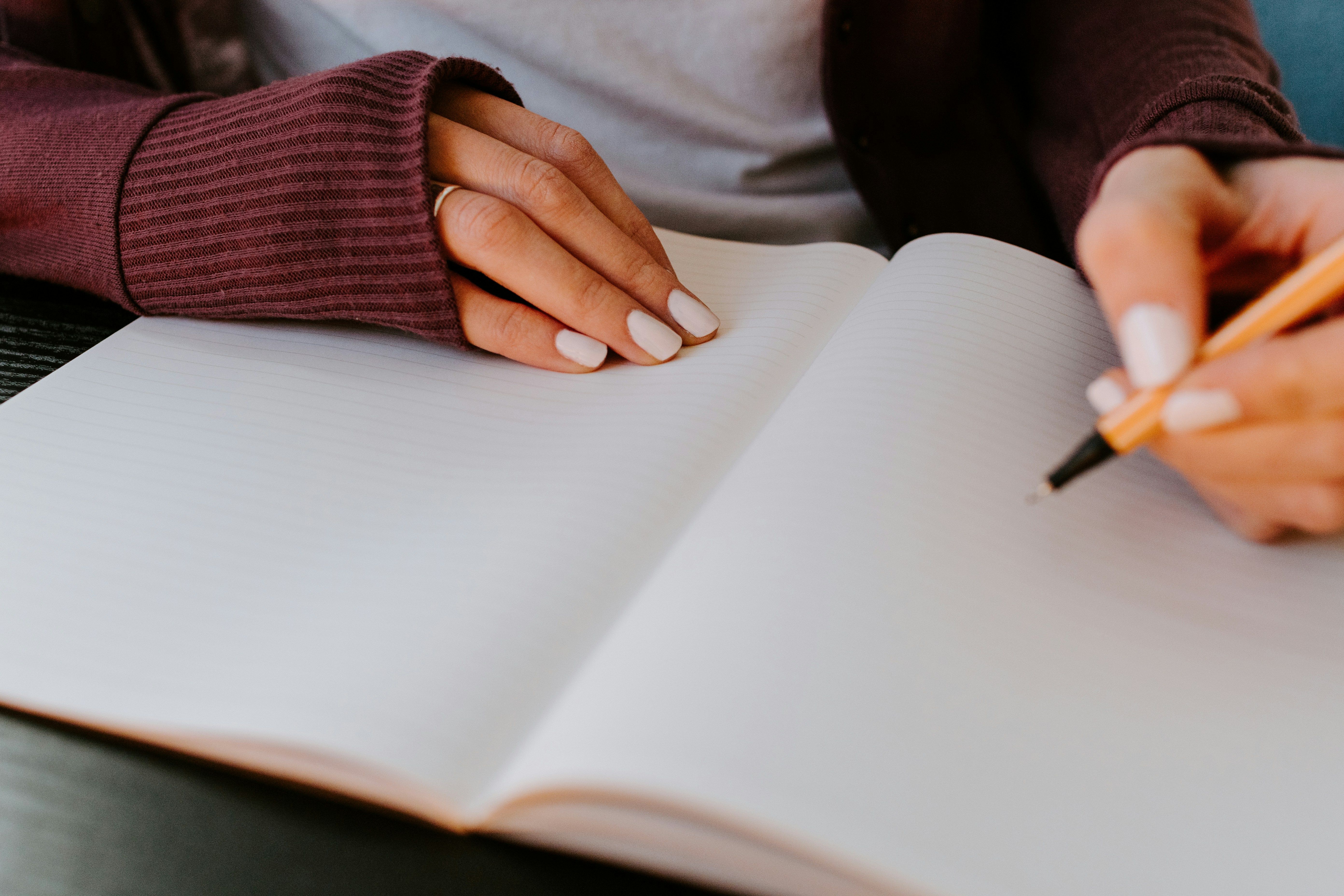 Hand poised to write in a blank notebook