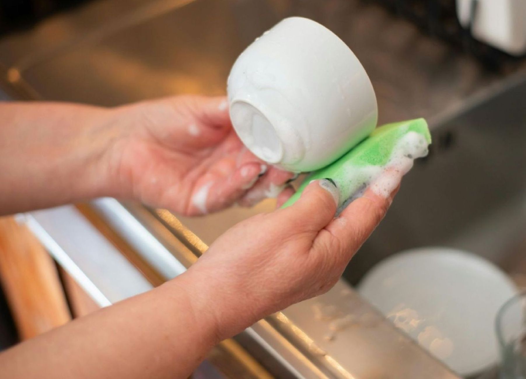 Hands gently washing a coffee cup getting started on house chores