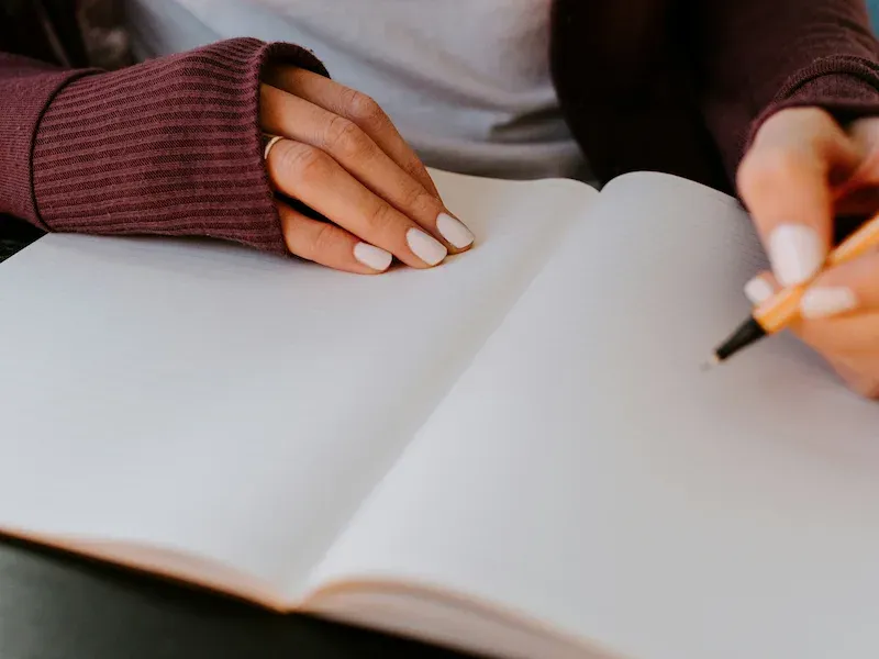 Hand poised to write in a blank notebook
