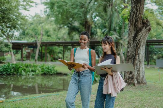 Two students walking together on campus with folders open