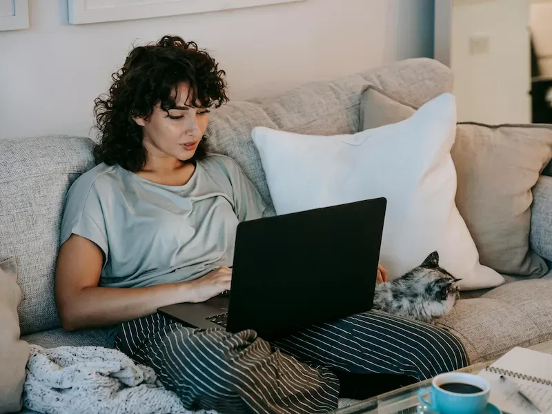 student sitting on the couch looking at her laptop