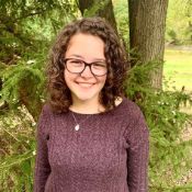 Hannah G, Academic and Executive Function Coach at Coaching Academics, smiling outside standing in a grove of trees