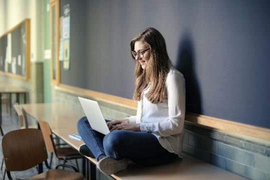 Student who has built better study skills sitting and smiling at their laptop.