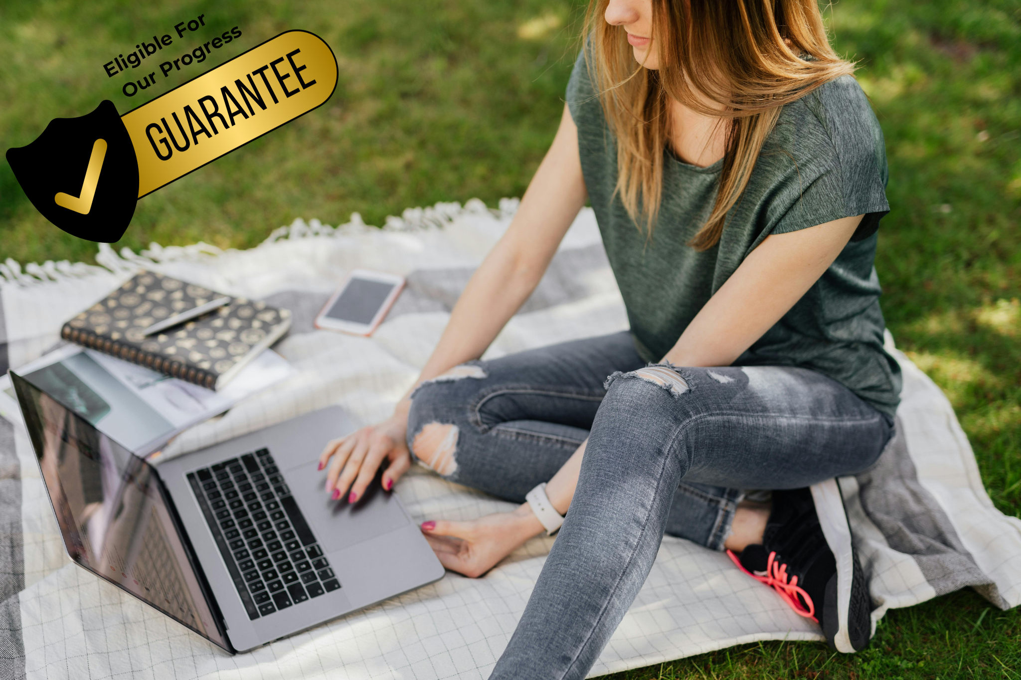 Student studying on laptop outside on a blanket.