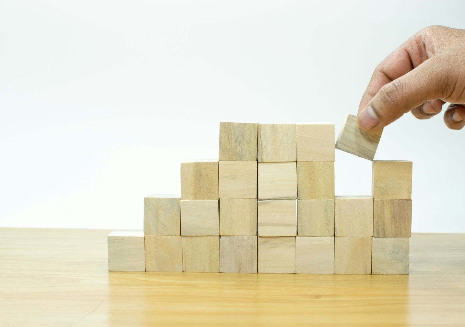 Simple wood blocks being stacked into neat rows symbolizing small, manageable pieces 