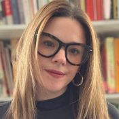 Madeleine, Executive Function & Mindset Coach smiling brightly at the camera in front of a neat bookshelf