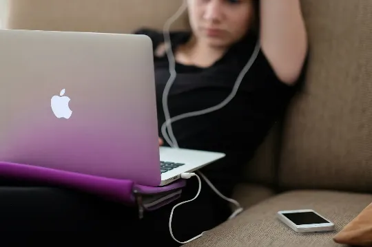 Two students working on laptops at a table.