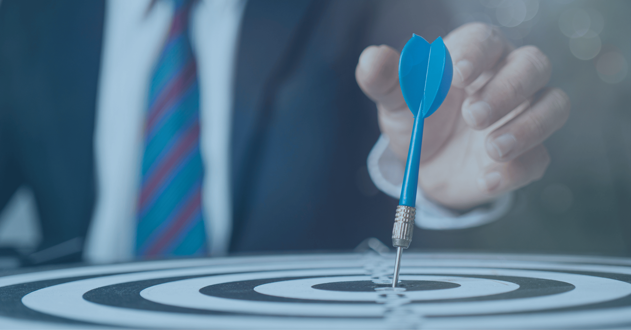 Businessman aiming a blue dart at the center of a target, representing Reyada’s mission to deliver precise and impactful digital solutions