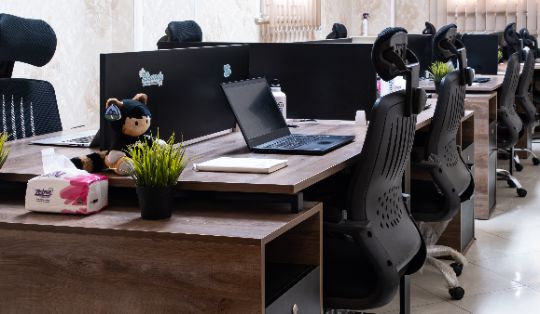 Modern open office workspace at Reyada with tech setup and team branding