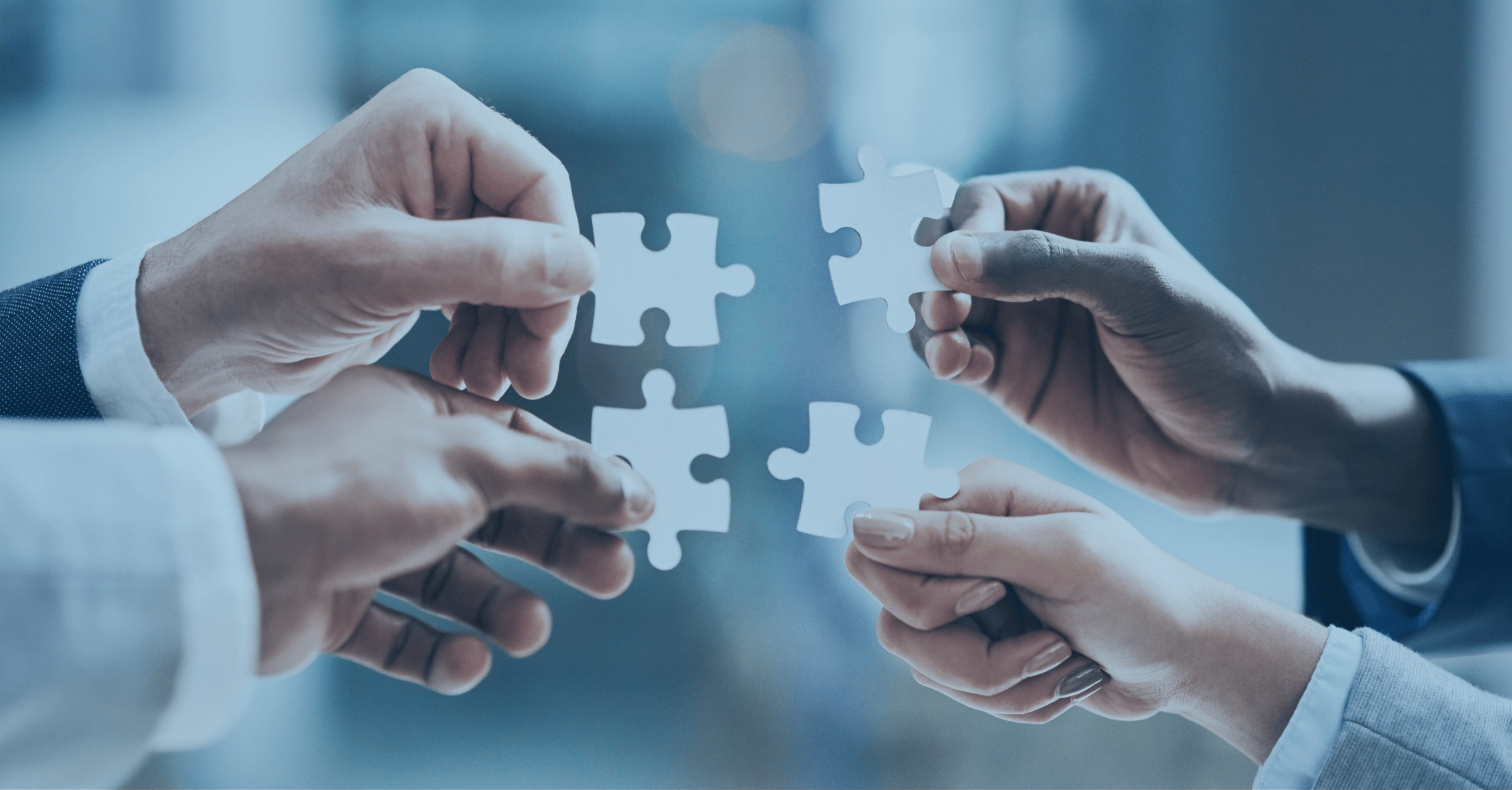 Four hands collaboratively connecting puzzle pieces, symbolizing Reyada’s core values of teamwork, integrity, innovation, and alignment